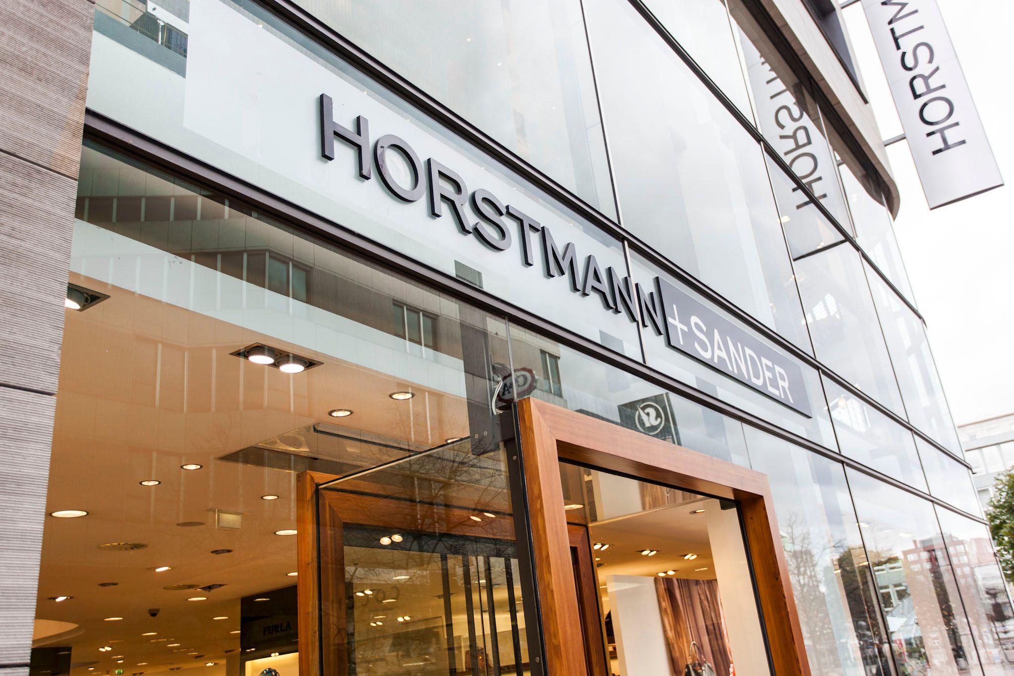 A modern glass building facade displaying the 'HORSTMANN & SANDER' store sign.