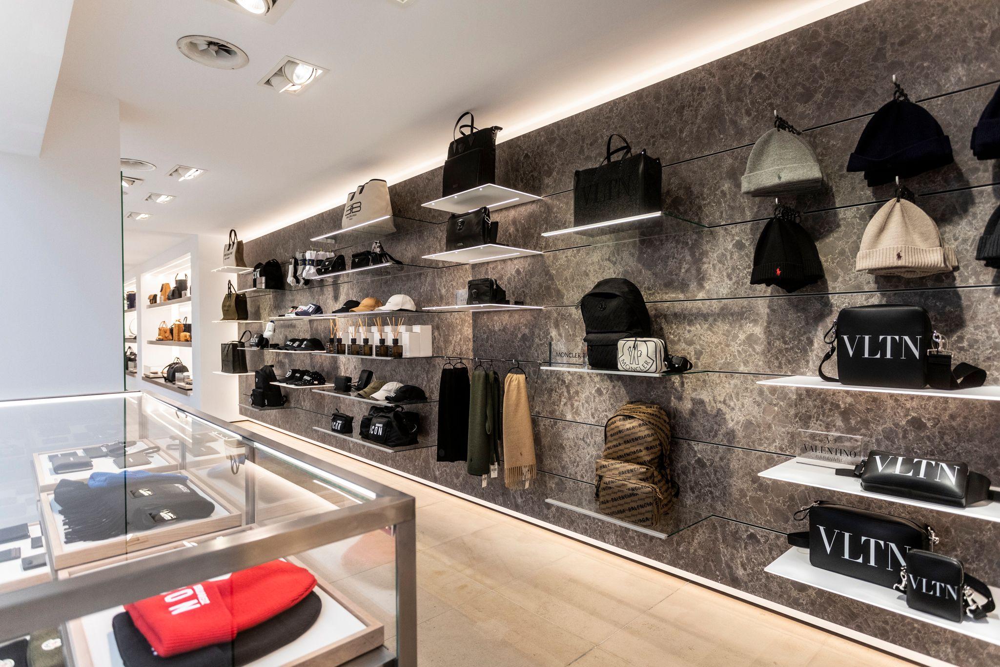 A sleek retail wall display featuring Valentino hats, bags, and accessories on illuminated shelves.