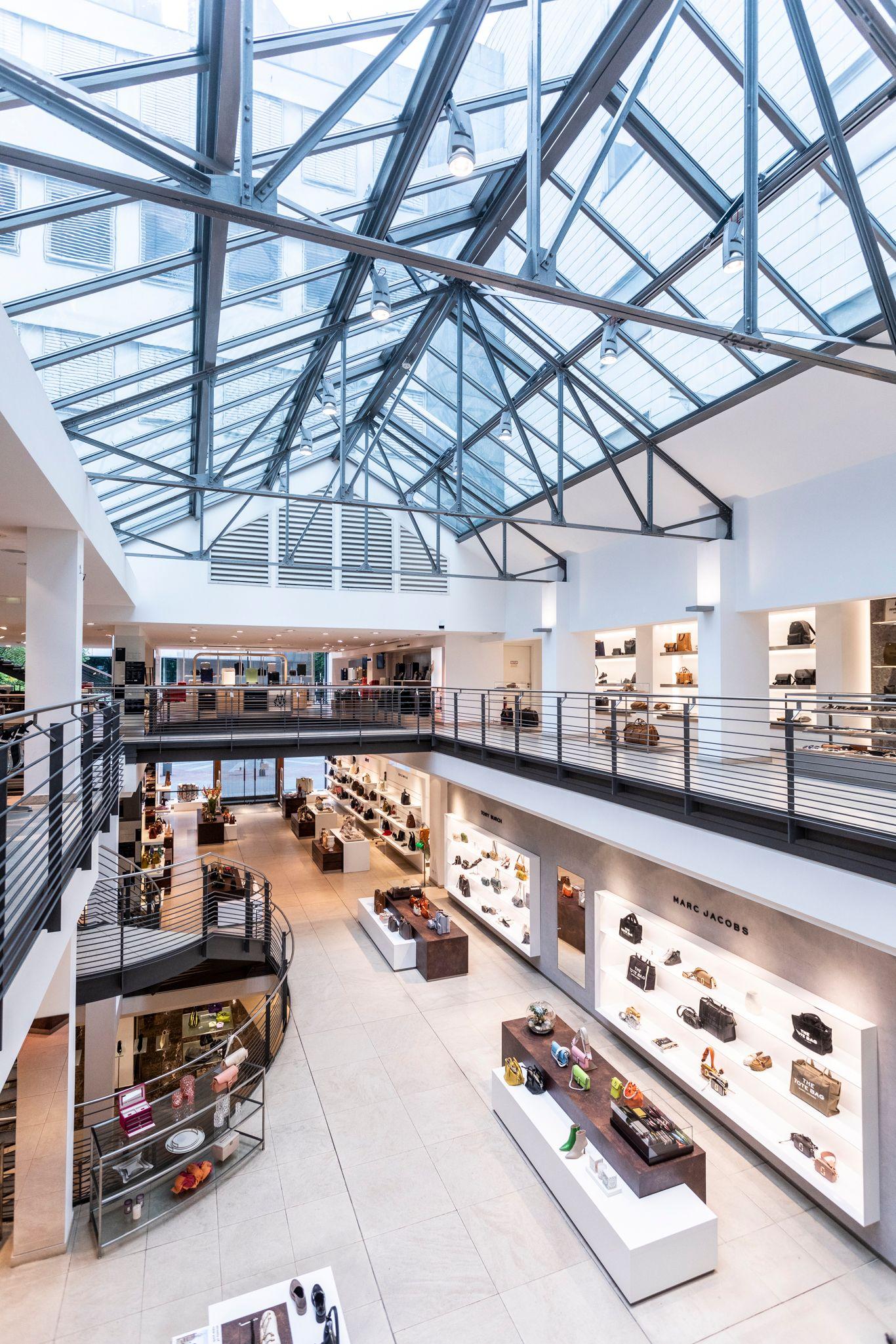 An expansive multi-level store interior with a glass skylight ceiling and visible escalators.