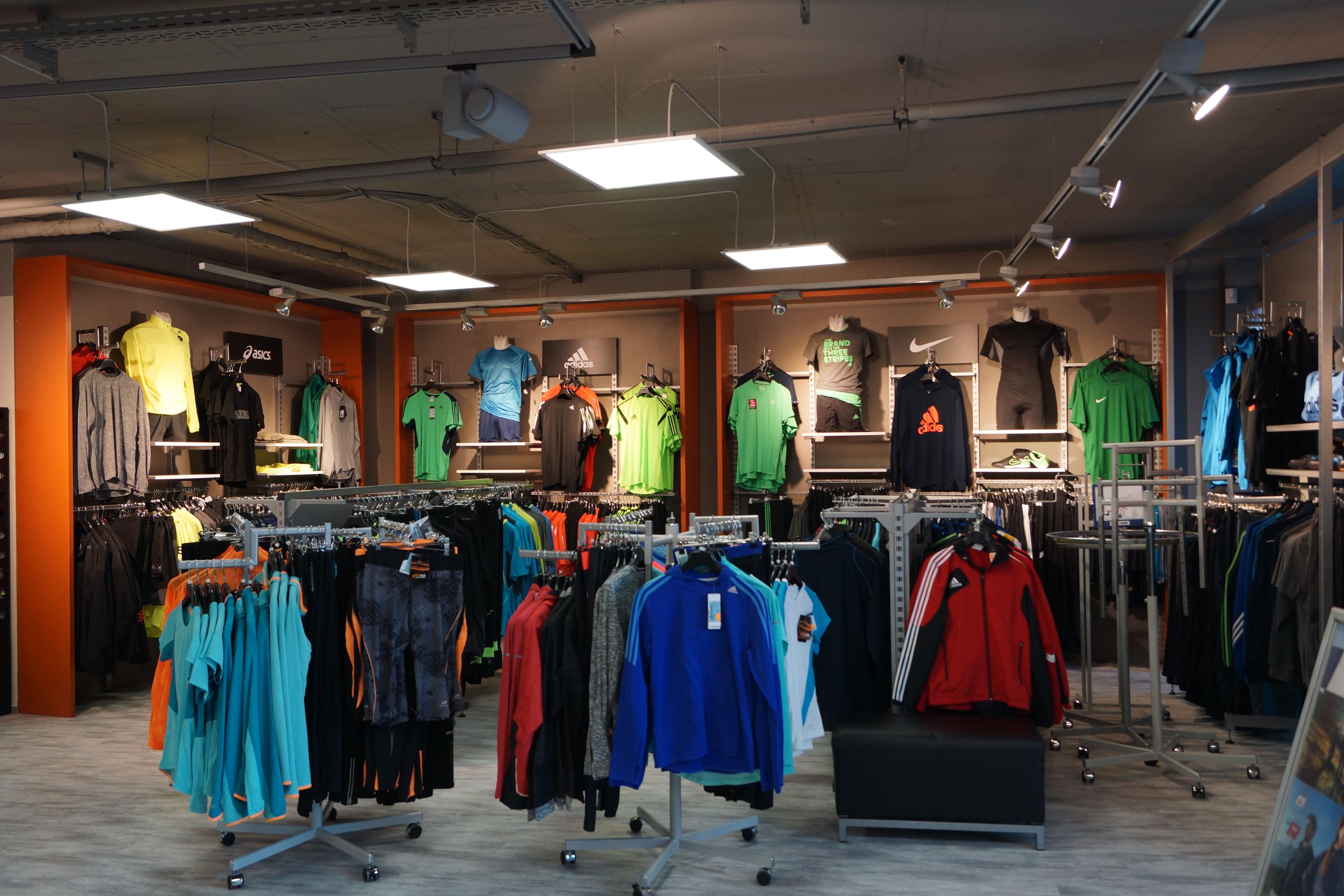 Indoor clothing store featuring racks and wall displays of colorful activewear and sports apparel.