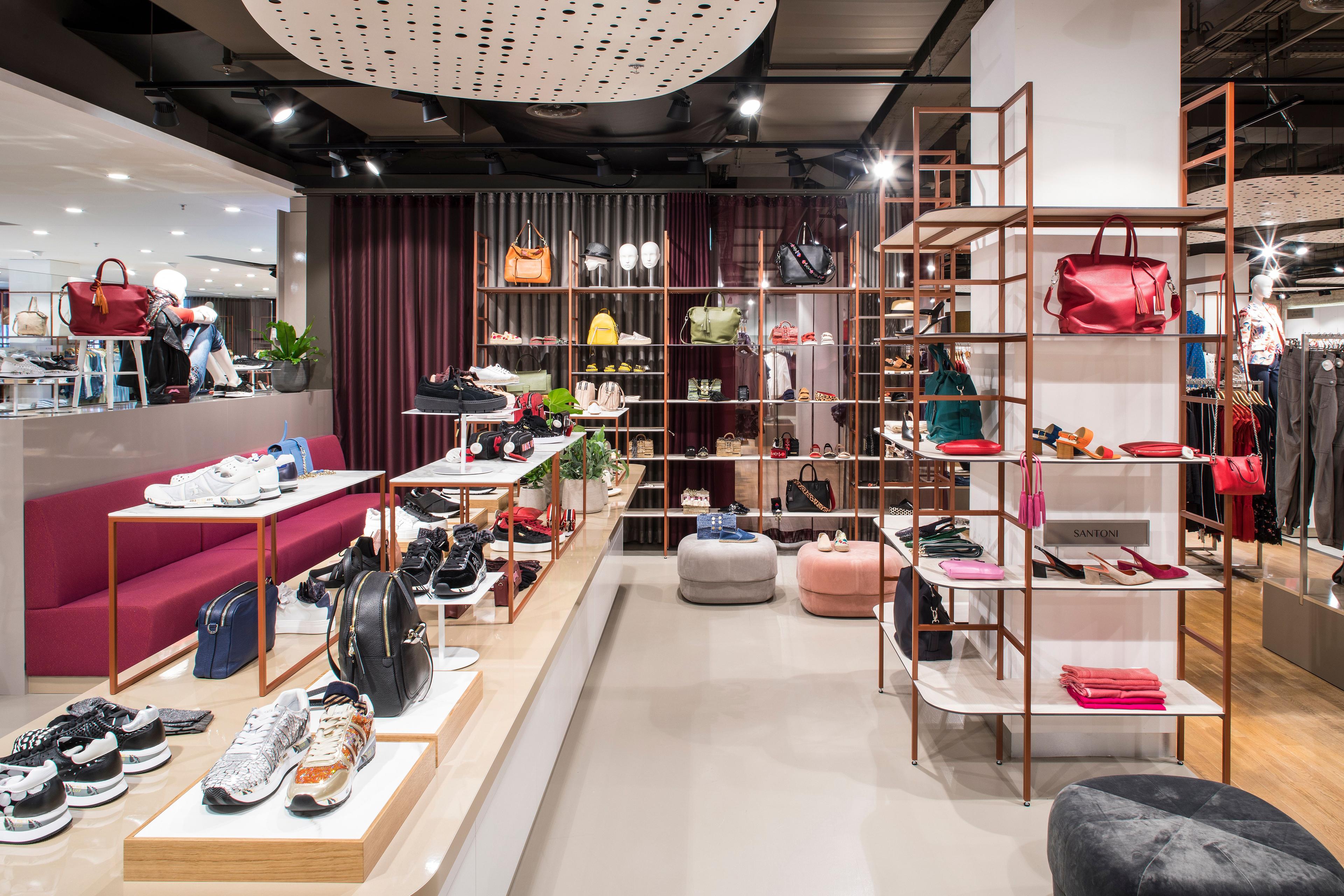 Modern retail store interior featuring displays of shoes, handbags, and fashion accessories.