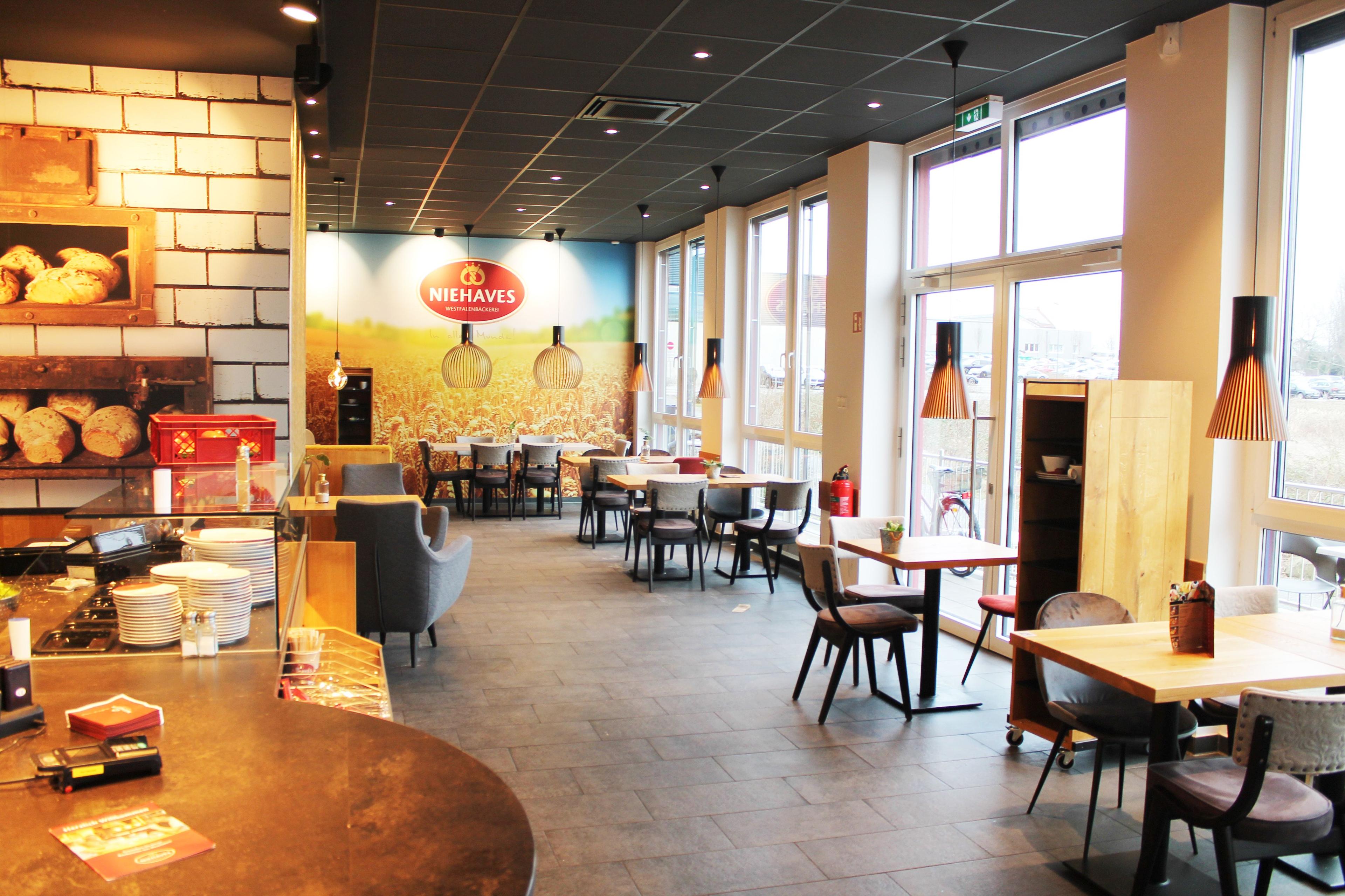 Modern cafe interior with tables, chairs, large windows, and a colorful farm mural.