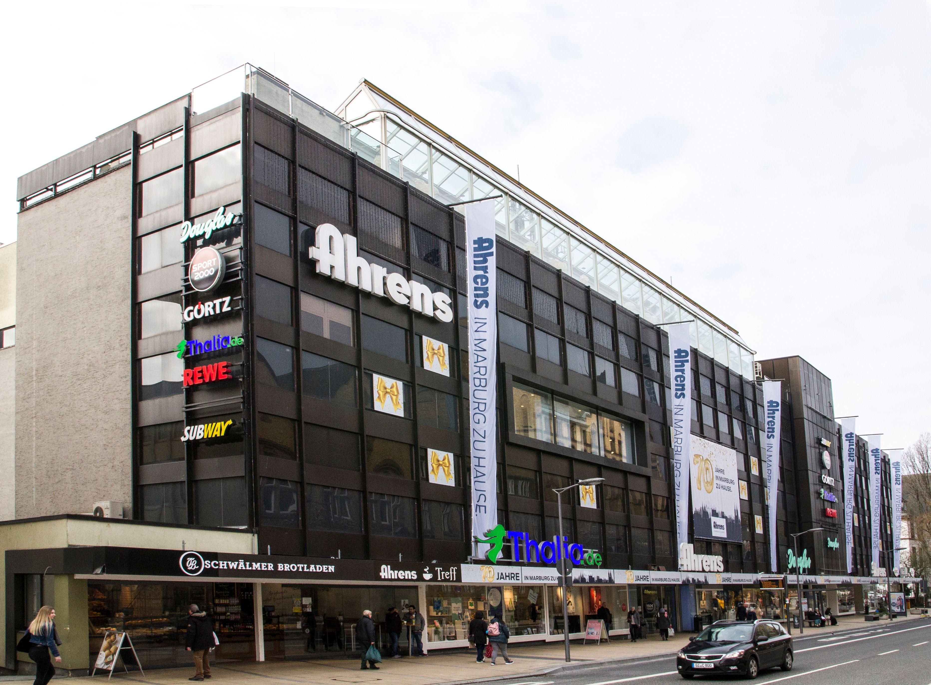 Large modern Ahrens department store building with multiple commercial signs on its dark facade.