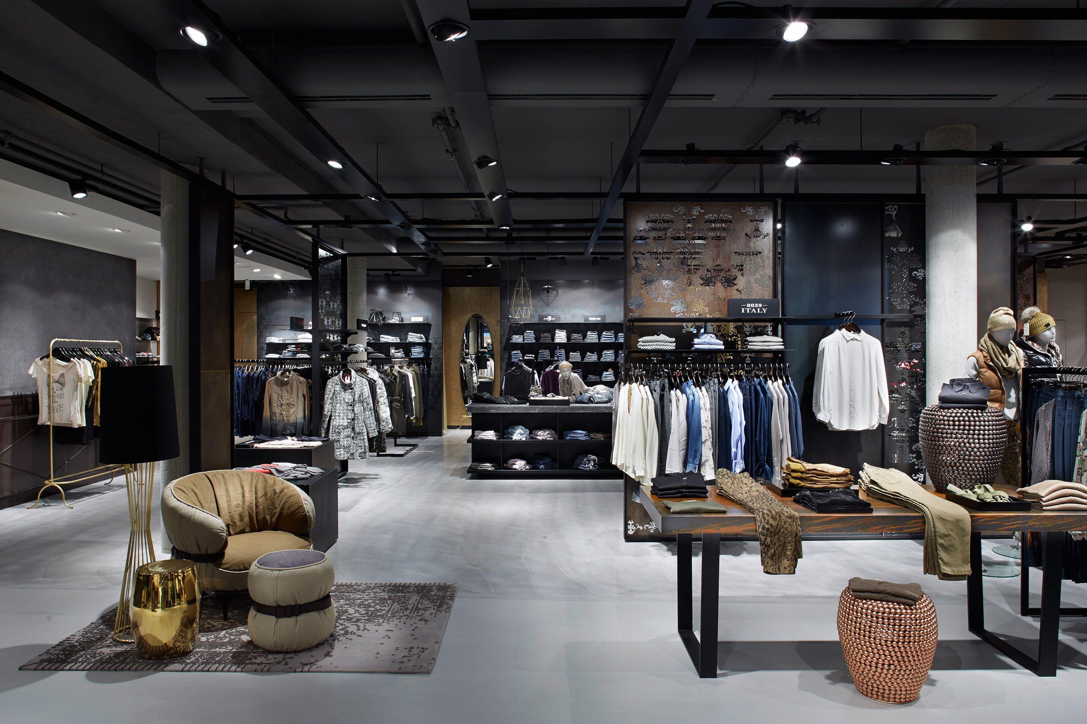 Interior of a modern men's clothing store with dark ceilings and organized apparel displays.