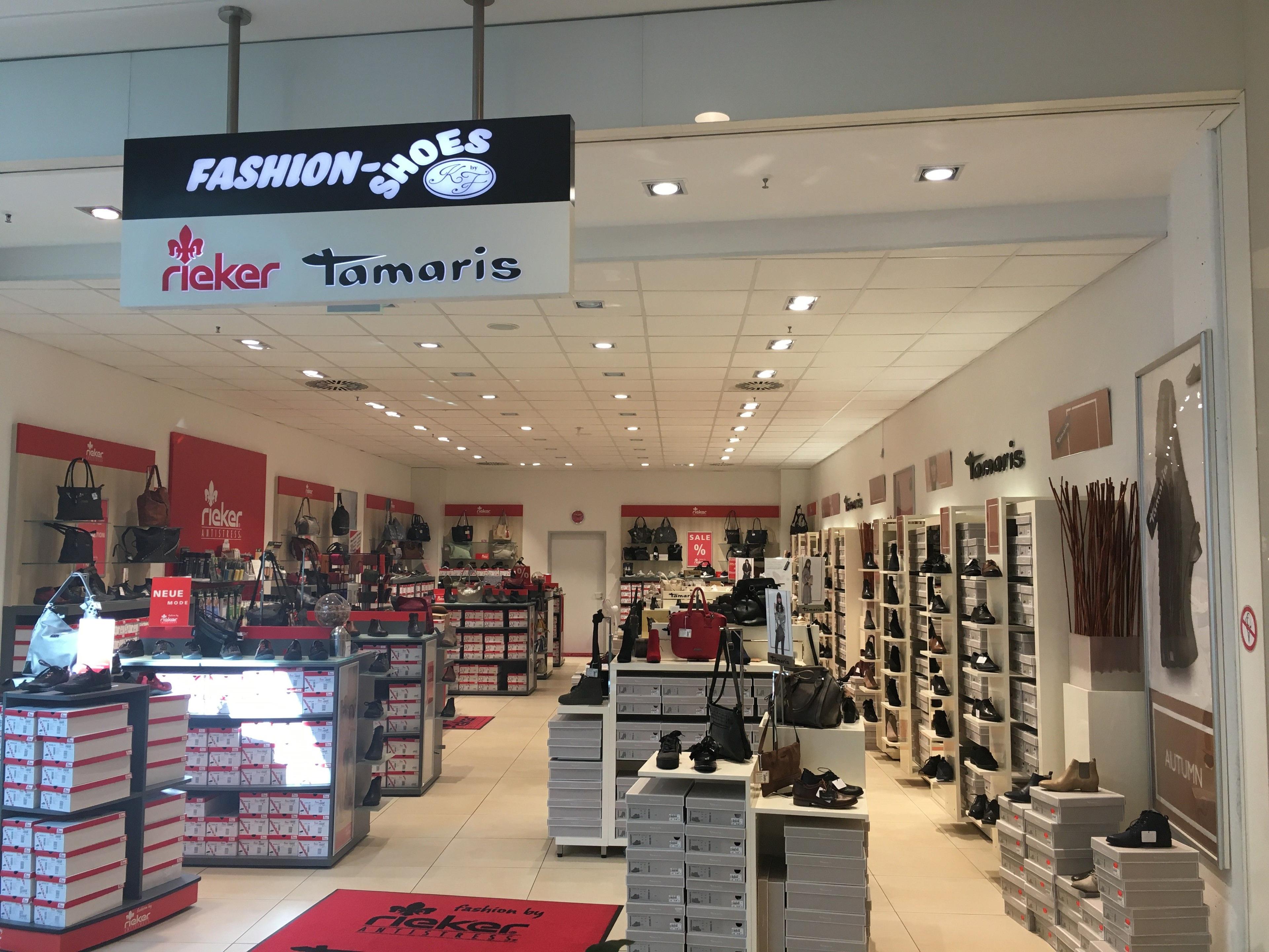 Interior of a brightly lit shoe store featuring rieker and Tamaris brands.