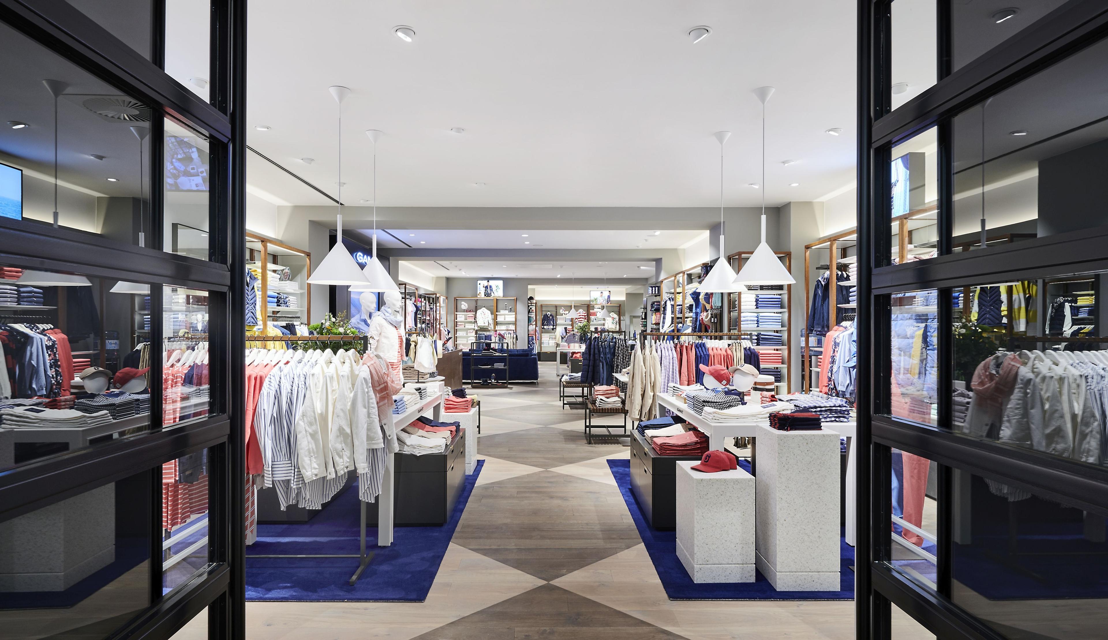 View through open doors into a bright, spacious clothing store with apparel displays.