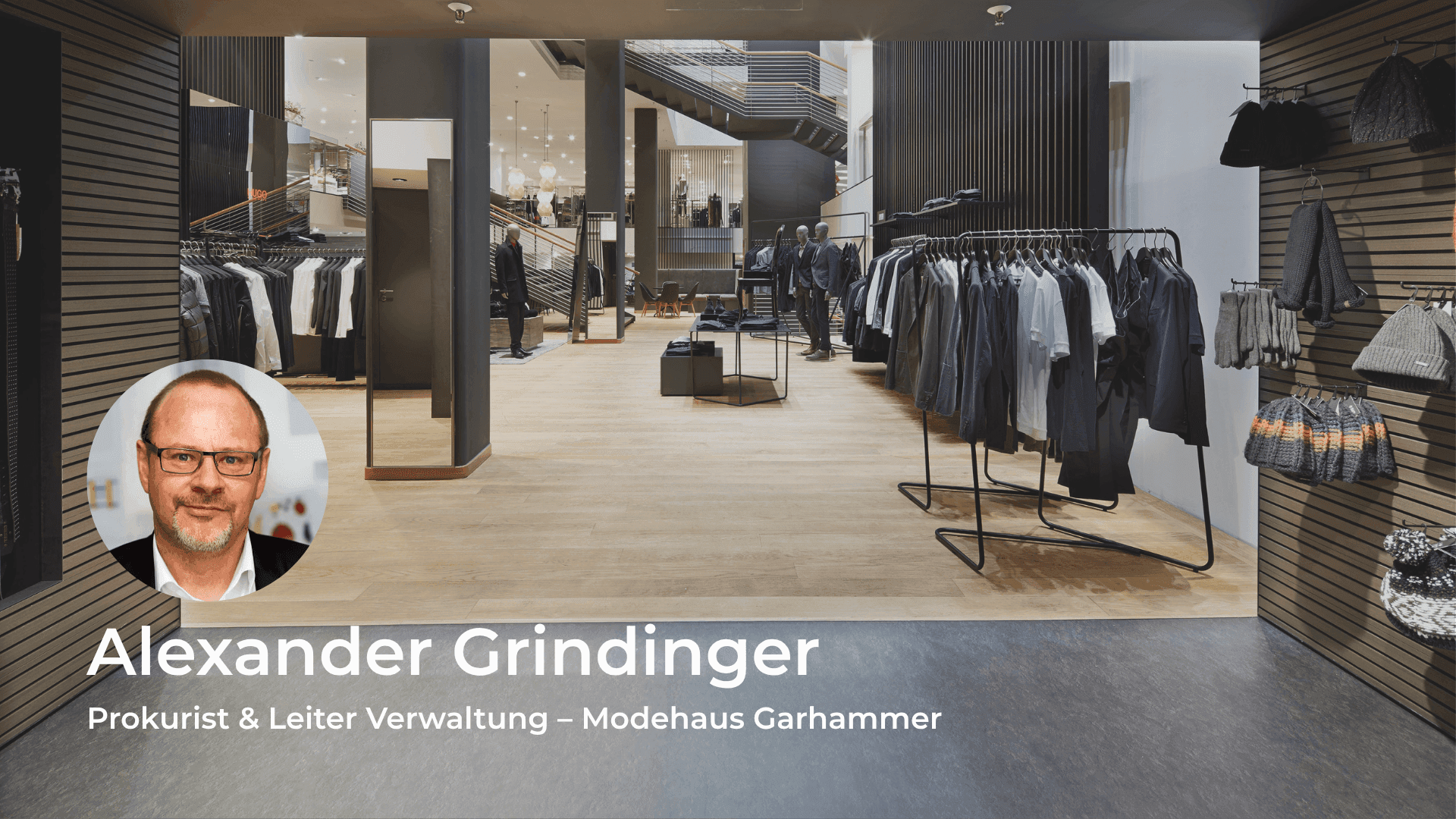 Headshot of Alexander Grindinger, Prokurist & Leiter Verwaltung, overlaid on a modern clothing store.
