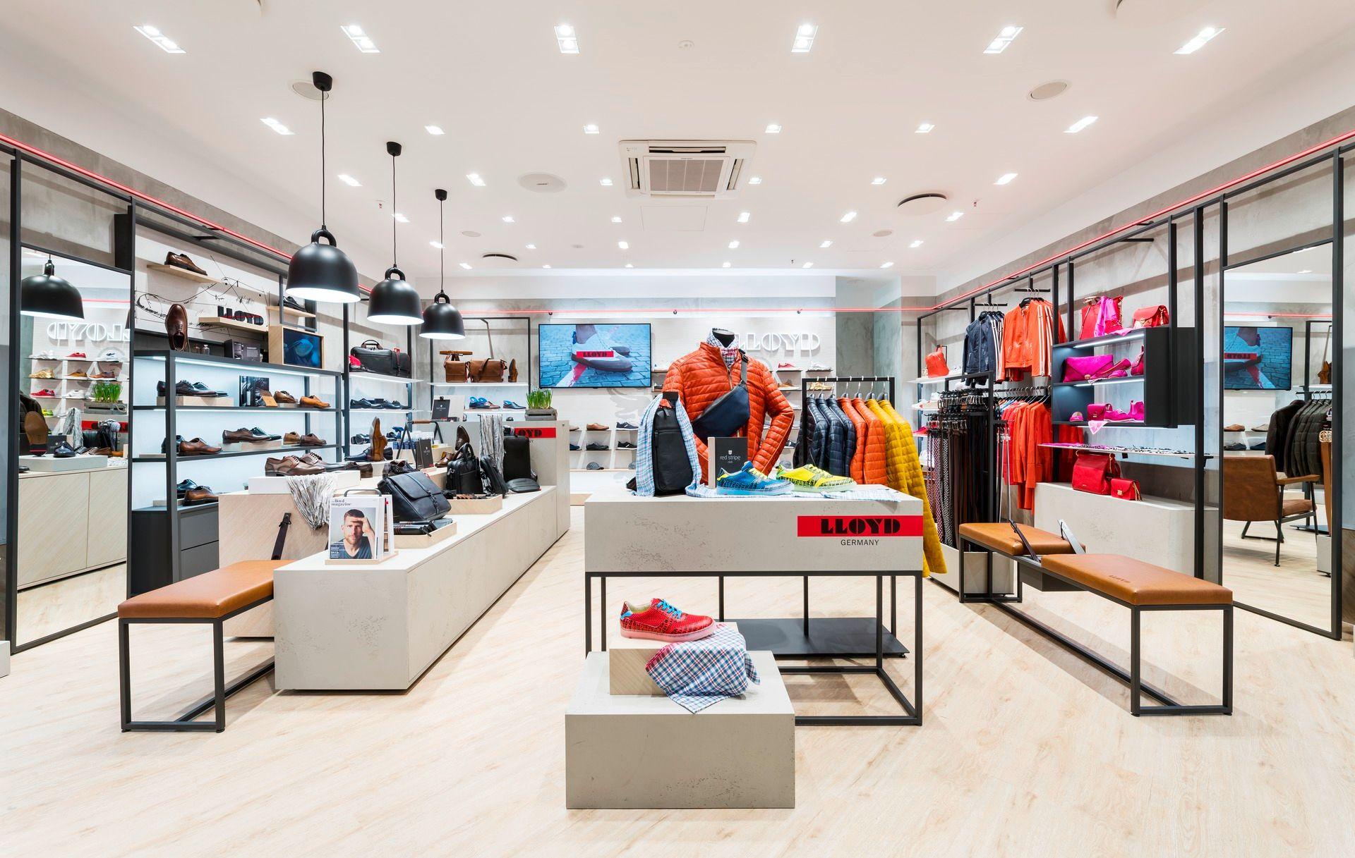 Modern retail store interior showcasing various shoes, colorful apparel, and accessories on display.