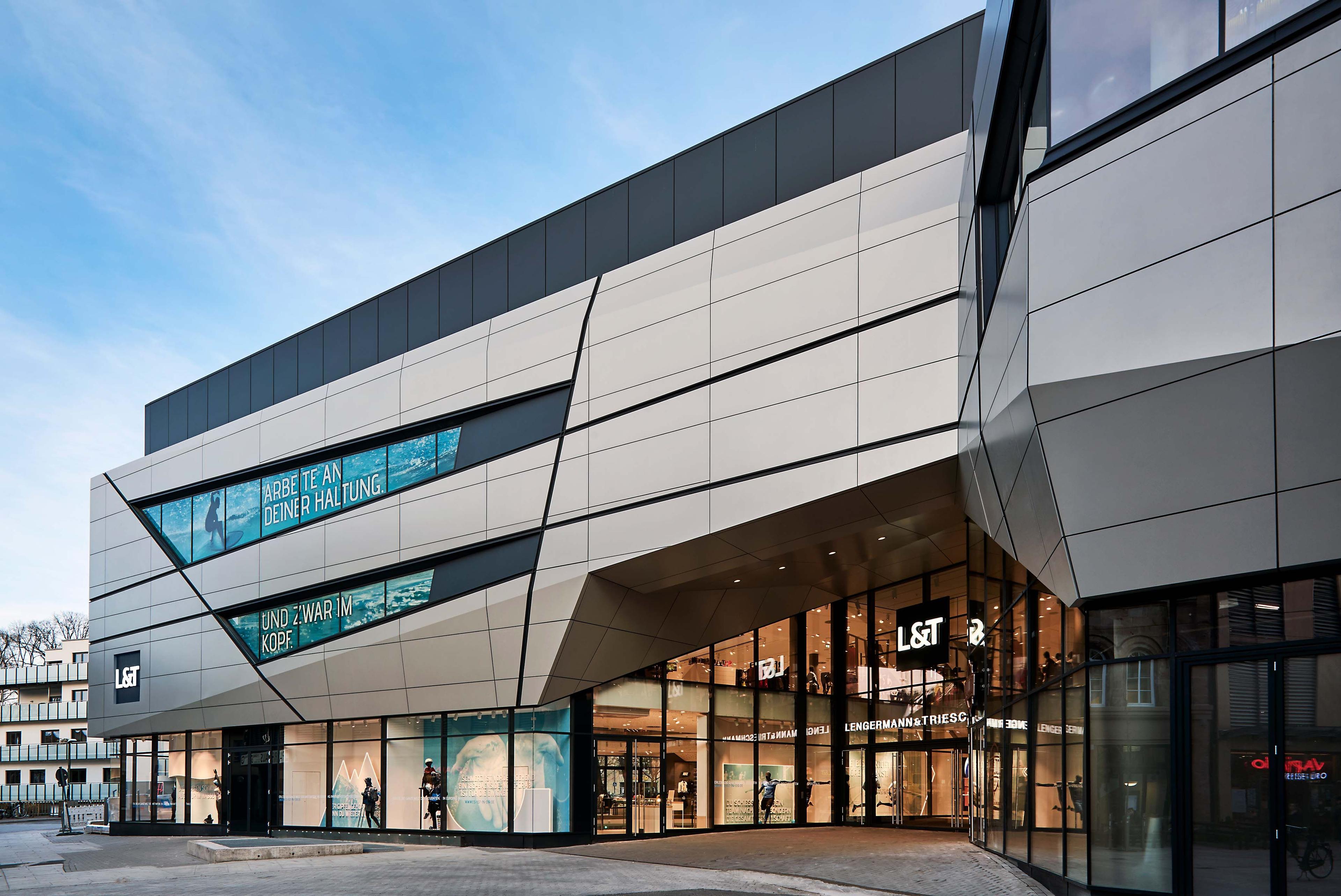 Modern building with angular design, glass facade, and large shop windows at entrance.