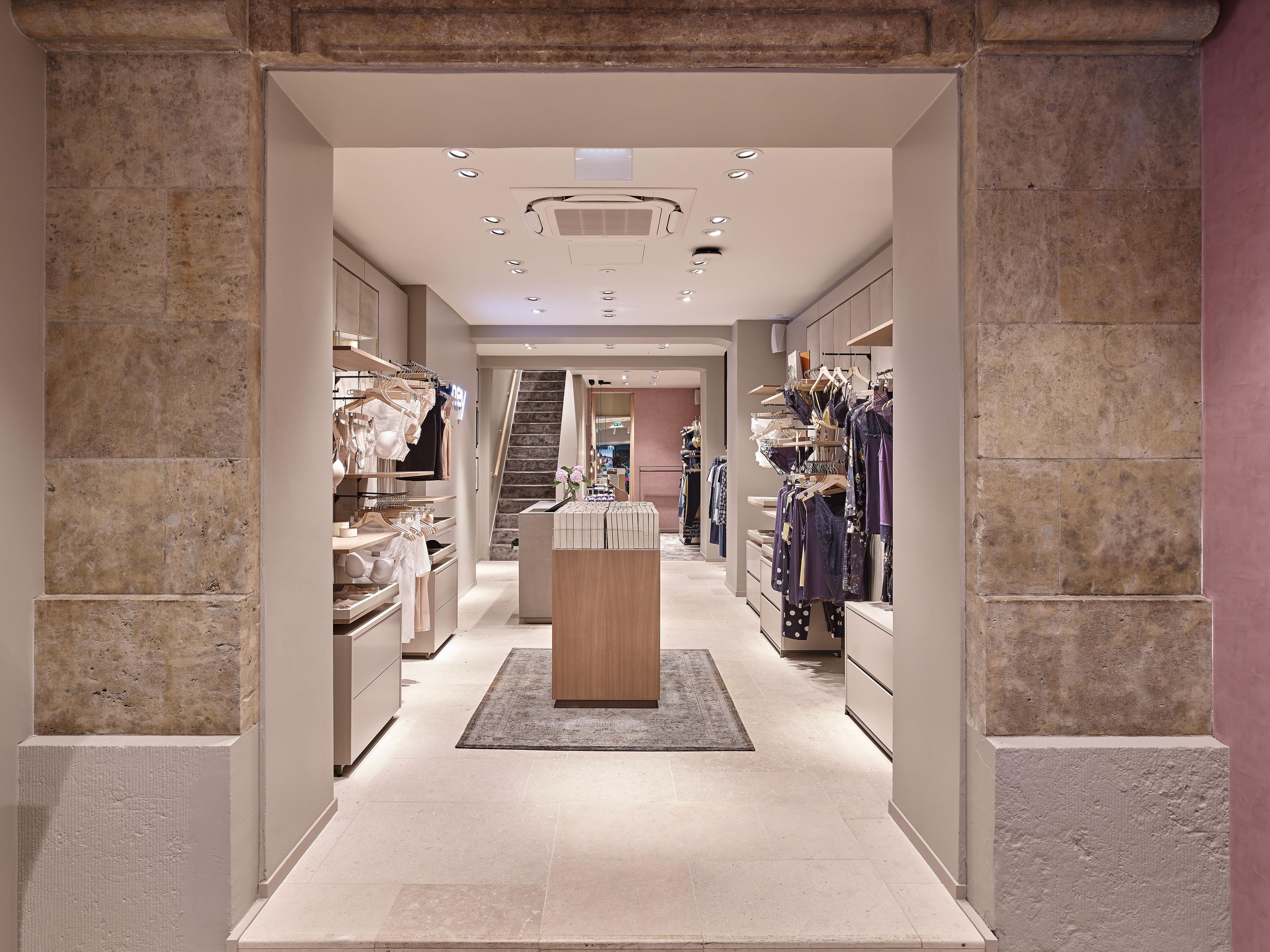 View from entrance into a modern retail store with clothing displays and a staircase.