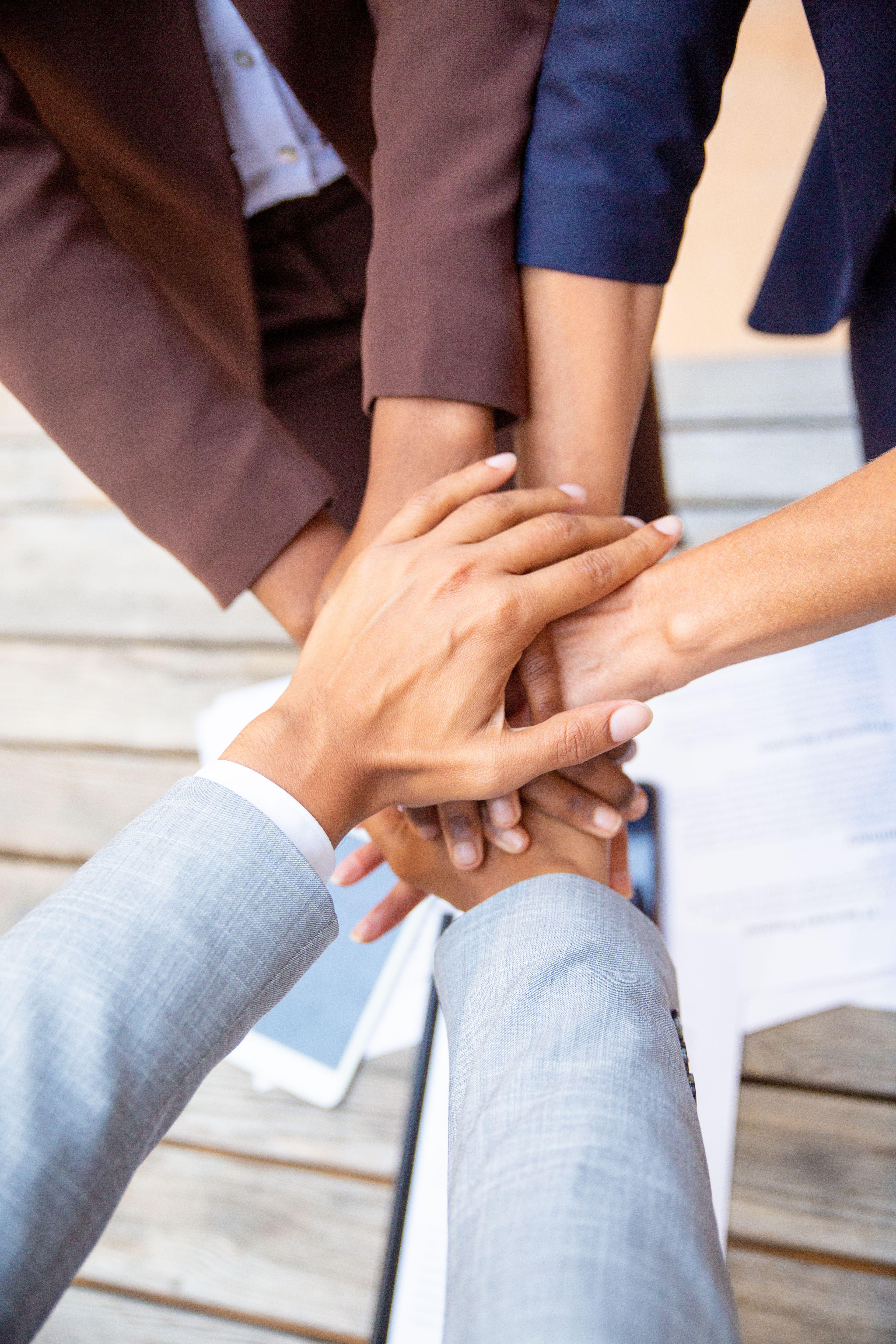 Diverse hands stacked together, symbolizing teamwork and unity among professionals.